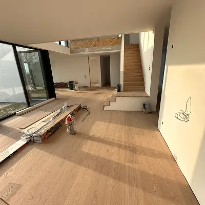 Offener Wohnbereich mit frisch verlegtem Holzboden und Treppe