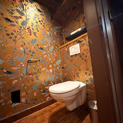 Gäste-WC mit Vogeltapete auf Ockergrund