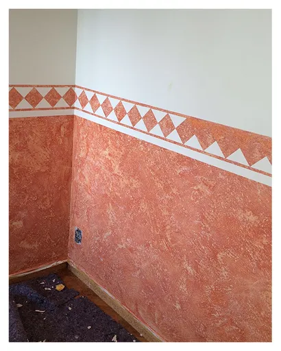 Terrakottafarbene Wischtechnik mit Rautenbordüre im Raum