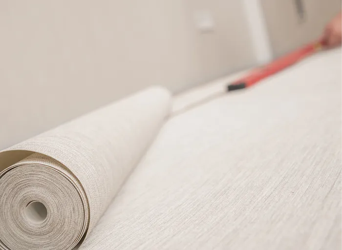 Tapetenrolle mit heller Strukturtapete wird ausgerollt