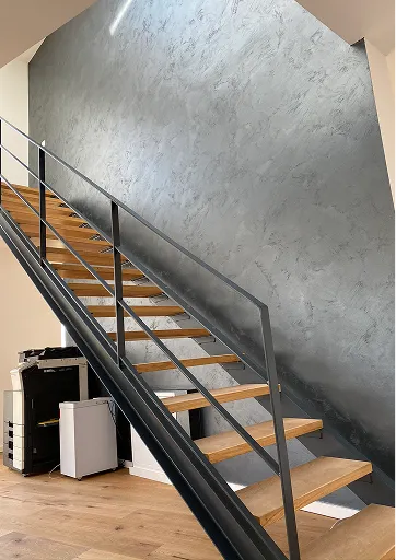 Graue Wand in Spachteltechnik neben einer Stahltreppe