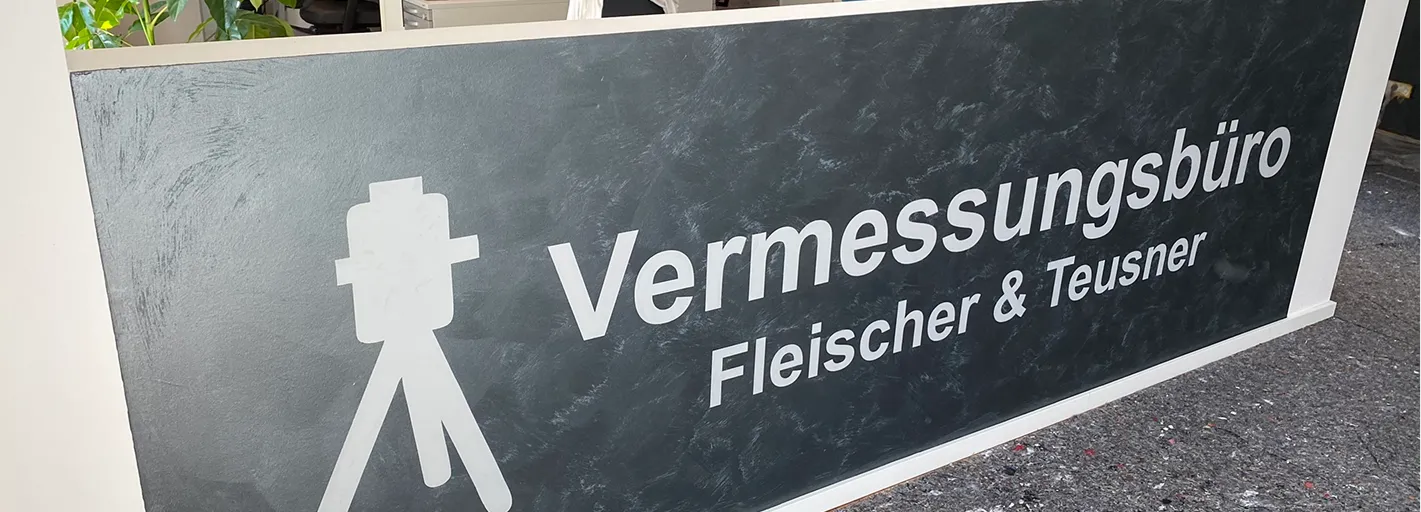Firmenschriftzug auf dunkler Wand in Spachteltechnik